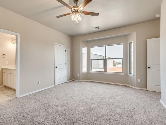 unfurnished bedroom with visible vents, light carpet, ceiling fan, ensuite bath, and baseboards