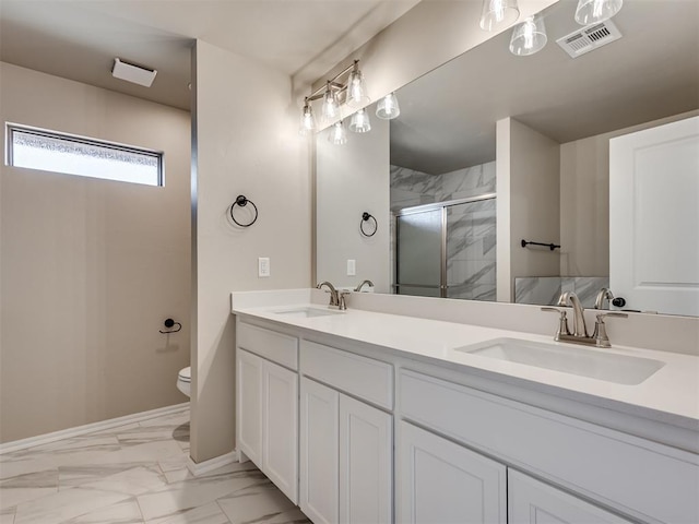 full bathroom with double vanity, marble finish floor, a shower stall, and a sink