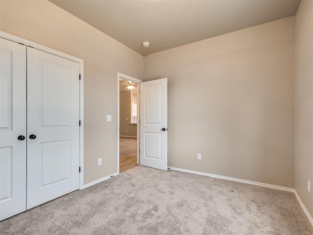 unfurnished bedroom featuring light carpet, a closet, and baseboards