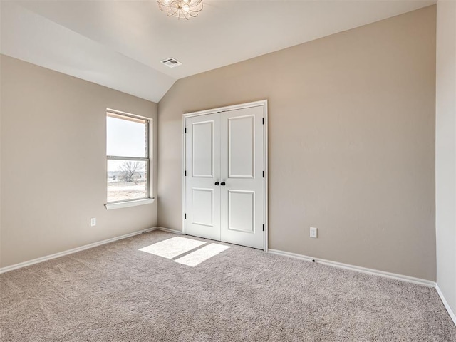 unfurnished bedroom featuring lofted ceiling, baseboards, visible vents, and carpet flooring