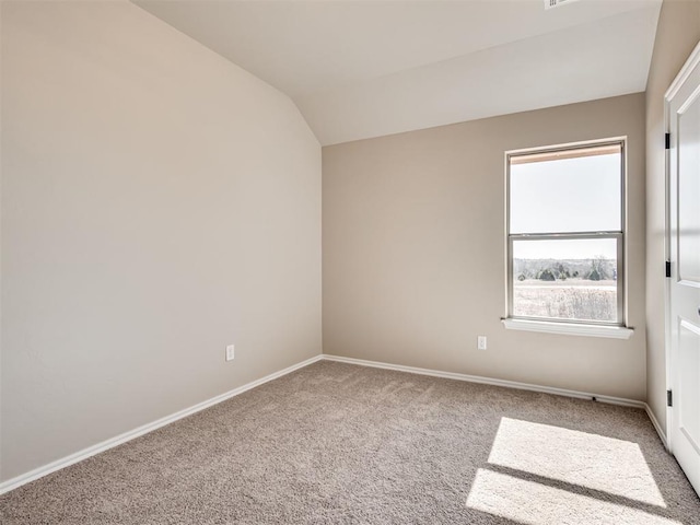 spare room with lofted ceiling, baseboards, and carpet