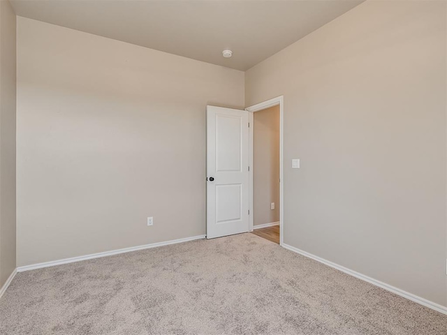 spare room with light carpet and baseboards