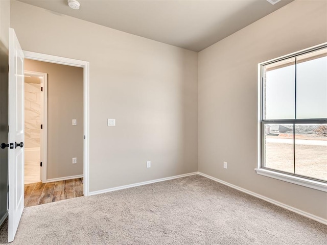 spare room featuring light colored carpet and baseboards