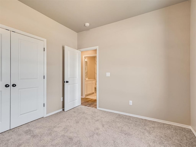 unfurnished bedroom featuring baseboards, a closet, and light colored carpet