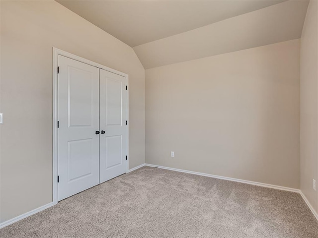 unfurnished bedroom with vaulted ceiling, carpet floors, a closet, and baseboards