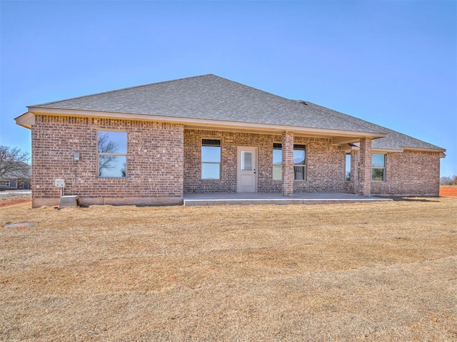 back of property with a shingled roof and brick siding