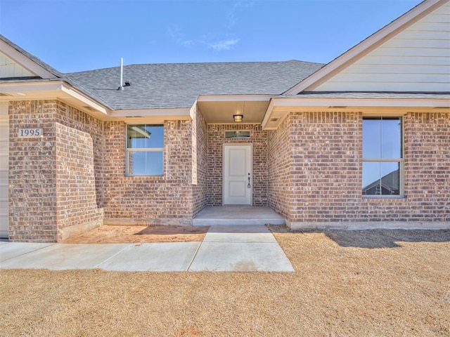 property entrance with brick siding and roof with shingles