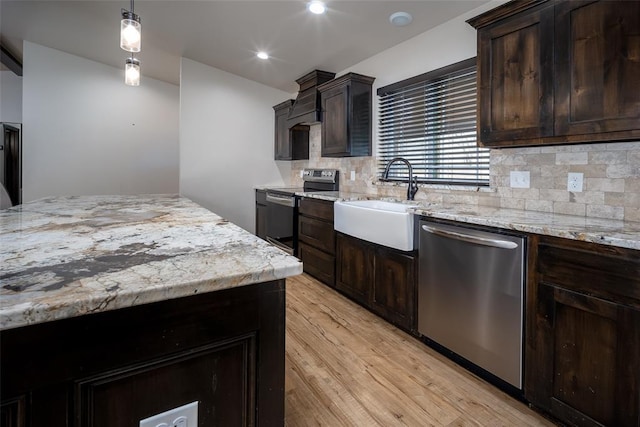 kitchen with decorative backsplash, light wood-type flooring, stainless steel appliances, sink, and decorative light fixtures