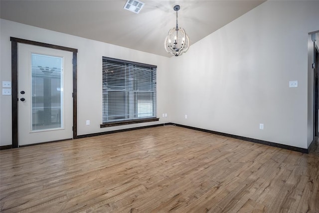 unfurnished room featuring light hardwood / wood-style flooring and an inviting chandelier