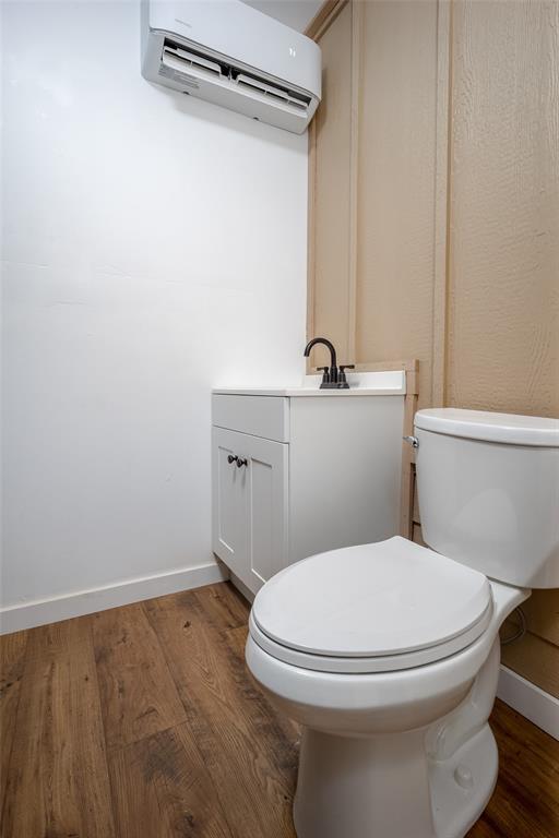 bathroom featuring a wall mounted AC, hardwood / wood-style floors, vanity, and toilet