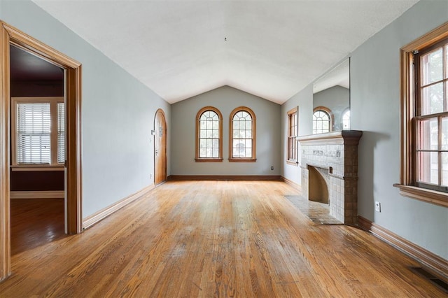 unfurnished living room with light hardwood / wood-style floors, lofted ceiling, and a fireplace