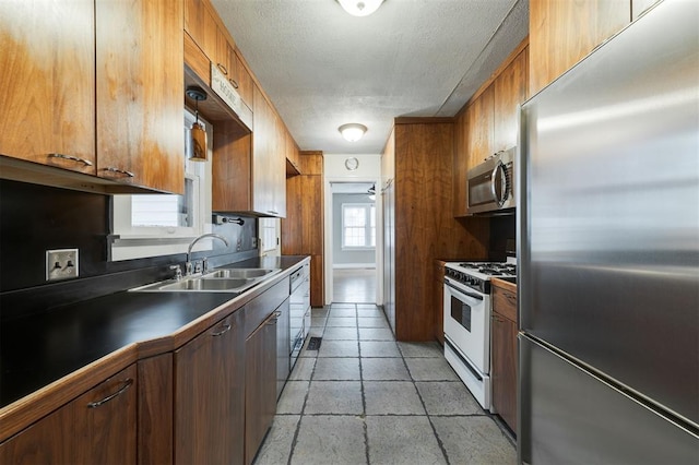 kitchen with ceiling fan, sink, stainless steel appliances, and a textured ceiling