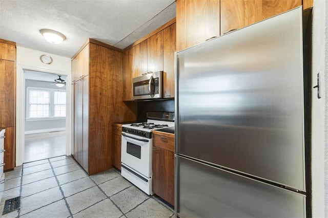 kitchen with ceiling fan, a textured ceiling, and appliances with stainless steel finishes