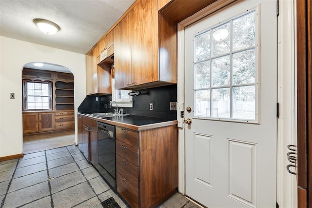 kitchen with a textured ceiling, black dishwasher, sink, and a wealth of natural light