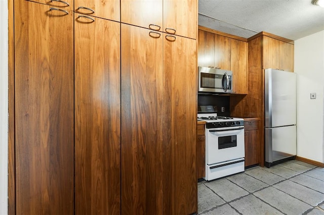 kitchen with light tile patterned floors, a textured ceiling, and appliances with stainless steel finishes