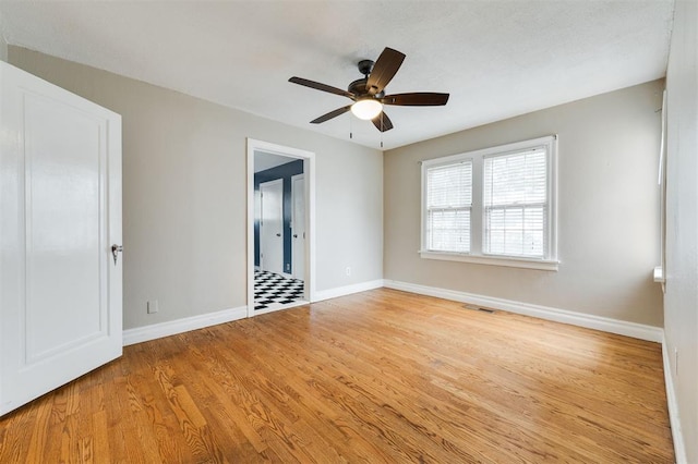 empty room with ceiling fan and light hardwood / wood-style floors