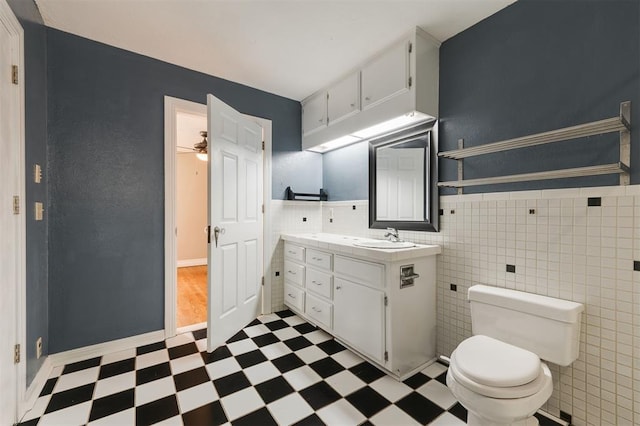 bathroom featuring ceiling fan, vanity, tile walls, and toilet