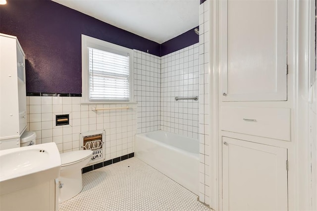 bathroom with tile patterned floors, toilet, tile walls, and tiled shower / bath