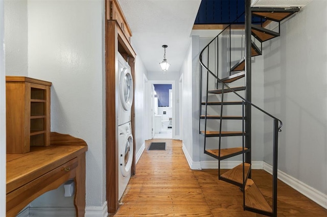 corridor with light hardwood / wood-style floors and stacked washer / dryer