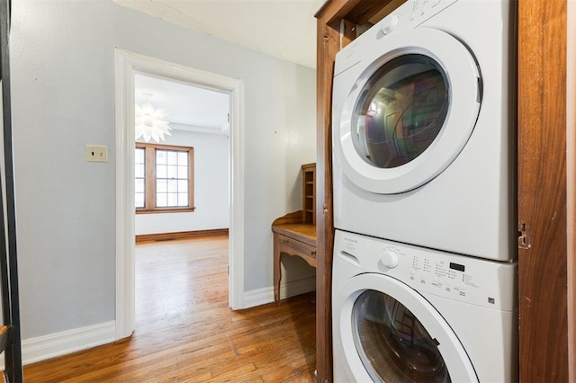 clothes washing area featuring light hardwood / wood-style floors and stacked washer / drying machine