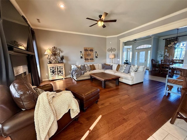 living room featuring ceiling fan with notable chandelier, wood-type flooring, and crown molding