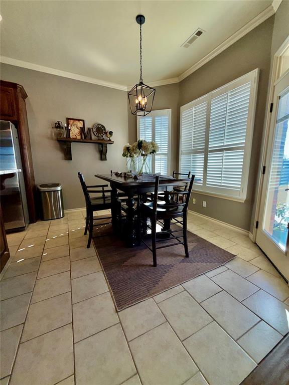 dining space with a notable chandelier, light tile patterned floors, and ornamental molding