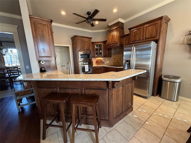 kitchen with a breakfast bar, light tile patterned floors, kitchen peninsula, and appliances with stainless steel finishes