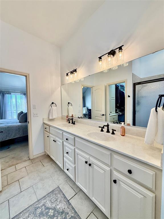 bathroom featuring tile patterned flooring, vanity, and a shower with door