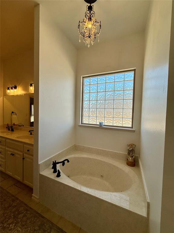 bathroom featuring a chandelier, a bath, and vanity