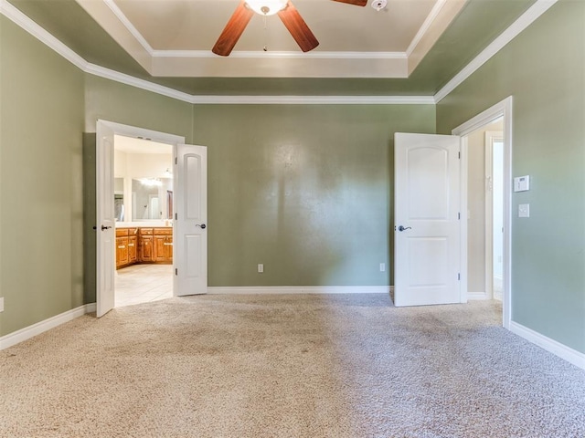 carpeted spare room featuring crown molding, a tray ceiling, and ceiling fan