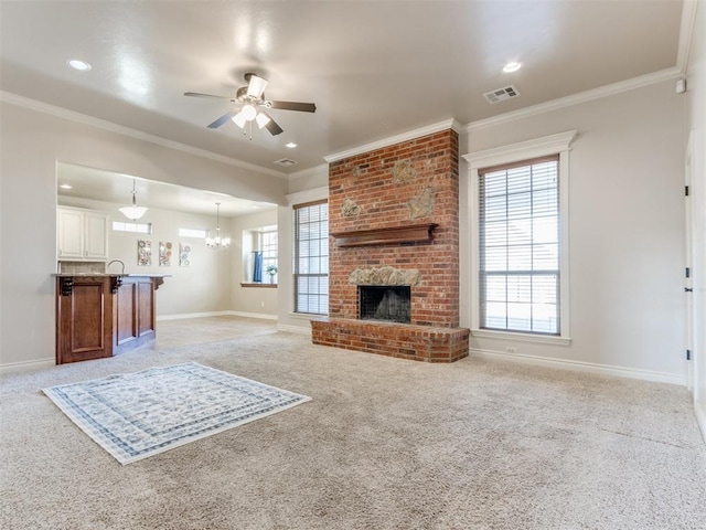 carpeted living room featuring ornamental molding, a fireplace, and ceiling fan with notable chandelier