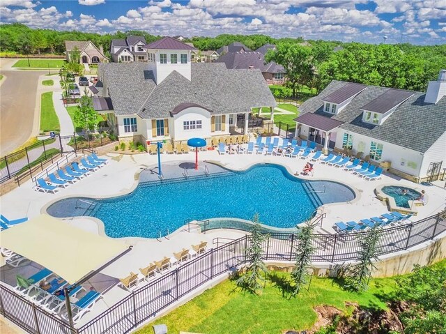 pool with a patio, fence, and a residential view