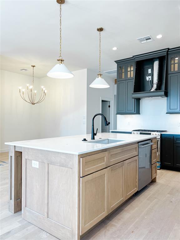 kitchen with visible vents, dishwasher, an island with sink, custom exhaust hood, and a sink