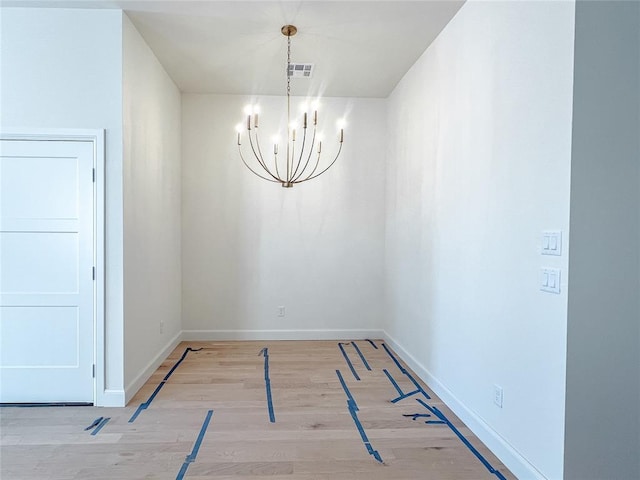 spare room featuring baseboards, light wood finished floors, visible vents, and a notable chandelier