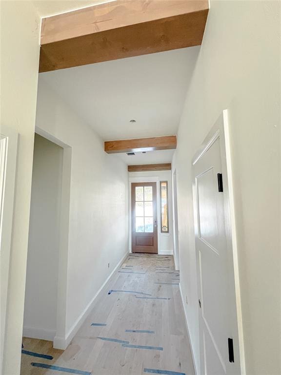 interior space featuring baseboards and beamed ceiling