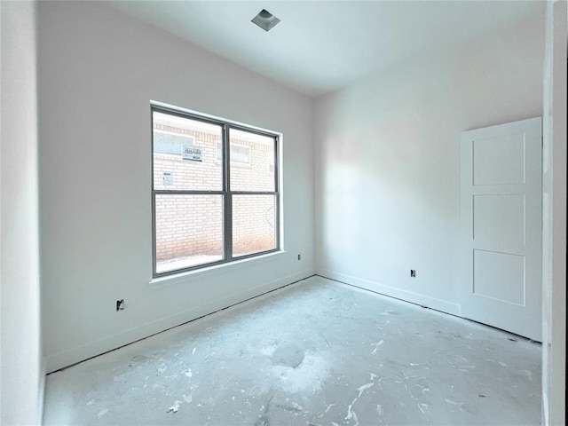 spare room featuring concrete floors and baseboards