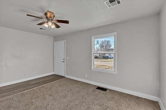 carpeted spare room featuring ceiling fan and a textured ceiling