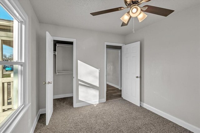 unfurnished bedroom with carpet flooring, ceiling fan, a textured ceiling, and a closet