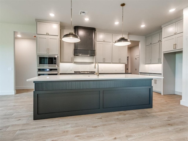 1203 Jaden Blvd, Tuttle, OK 73089 - kitchen with appliances with stainless steel finishes, wall chimney exhaust hood, tasteful backsplash, baseboards, and an island with sink