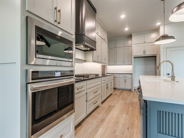 1203 Jaden Blvd, Tuttle, OK 73089 - kitchen with appliances with stainless steel finishes, wall chimney range hood, a sink, light wood finished floors, and recessed lighting