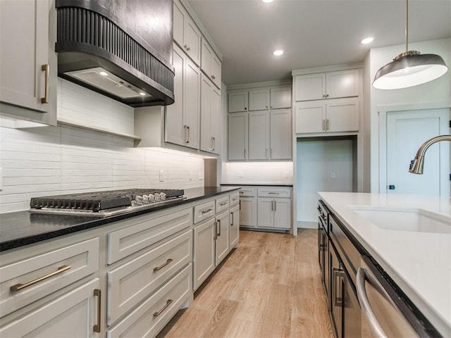 1203 Jaden Blvd, Tuttle, OK 73089 - kitchen with exhaust hood, appliances with stainless steel finishes, a sink, backsplash, and light wood-style floors