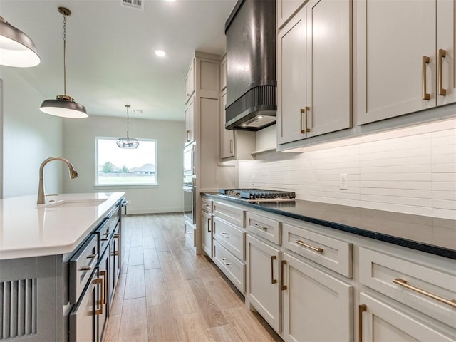 1203 Jaden Blvd, Tuttle, OK 73089 - kitchen with wall chimney exhaust hood, a sink, stainless steel appliances, light wood-style floors, and tasteful backsplash