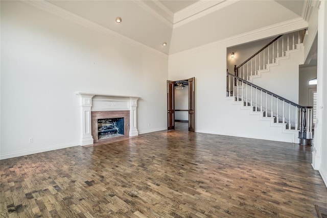 unfurnished living room with dark hardwood / wood-style flooring, a towering ceiling, and ornamental molding