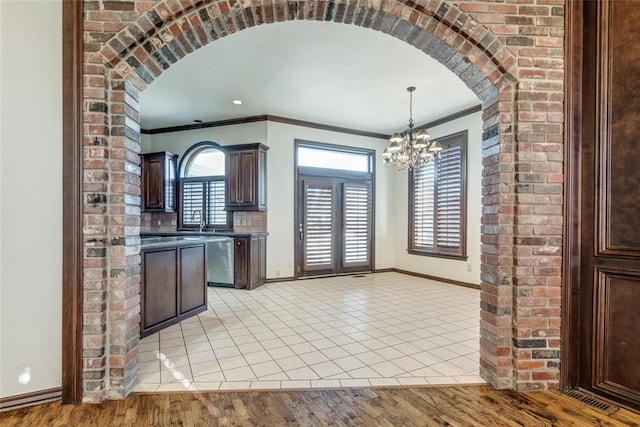 kitchen featuring dark brown cabinets, pendant lighting, light hardwood / wood-style floors, and crown molding