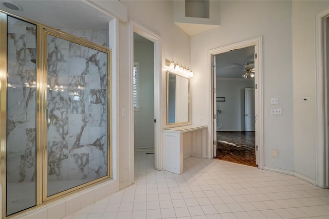 bathroom with ceiling fan, a shower with shower door, and ornamental molding