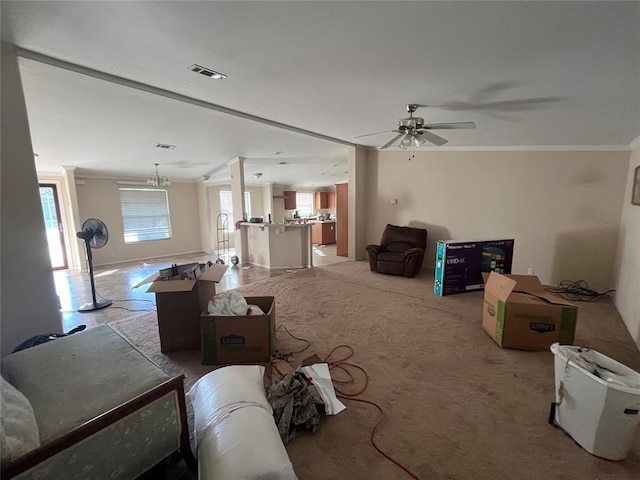 living room with plenty of natural light, light colored carpet, ceiling fan with notable chandelier, and ornamental molding