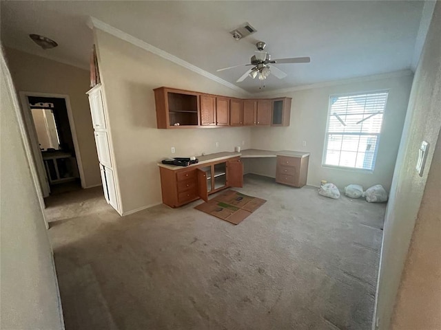 kitchen featuring light colored carpet, ceiling fan, crown molding, built in desk, and lofted ceiling