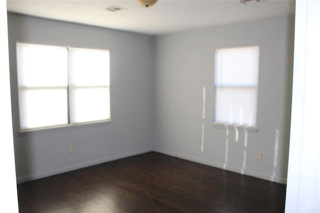 spare room with dark wood-type flooring and a healthy amount of sunlight