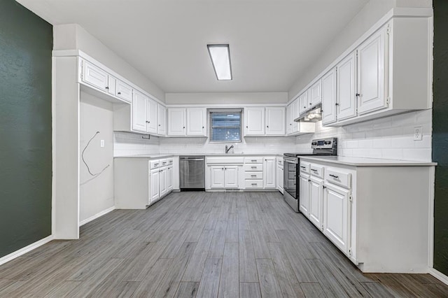 kitchen with white cabinets, appliances with stainless steel finishes, light wood-type flooring, and tasteful backsplash