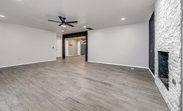 unfurnished living room featuring ceiling fan and a stone fireplace